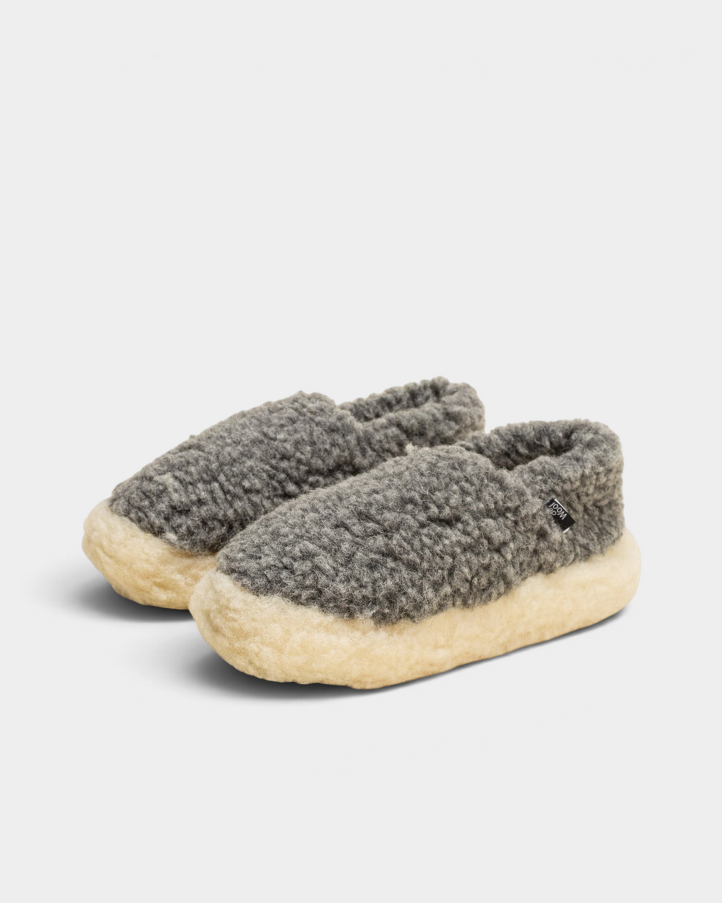 A pair of Rue De Wool The Nordic V2 slippers in iron grey and natural, angled front view on a cream background