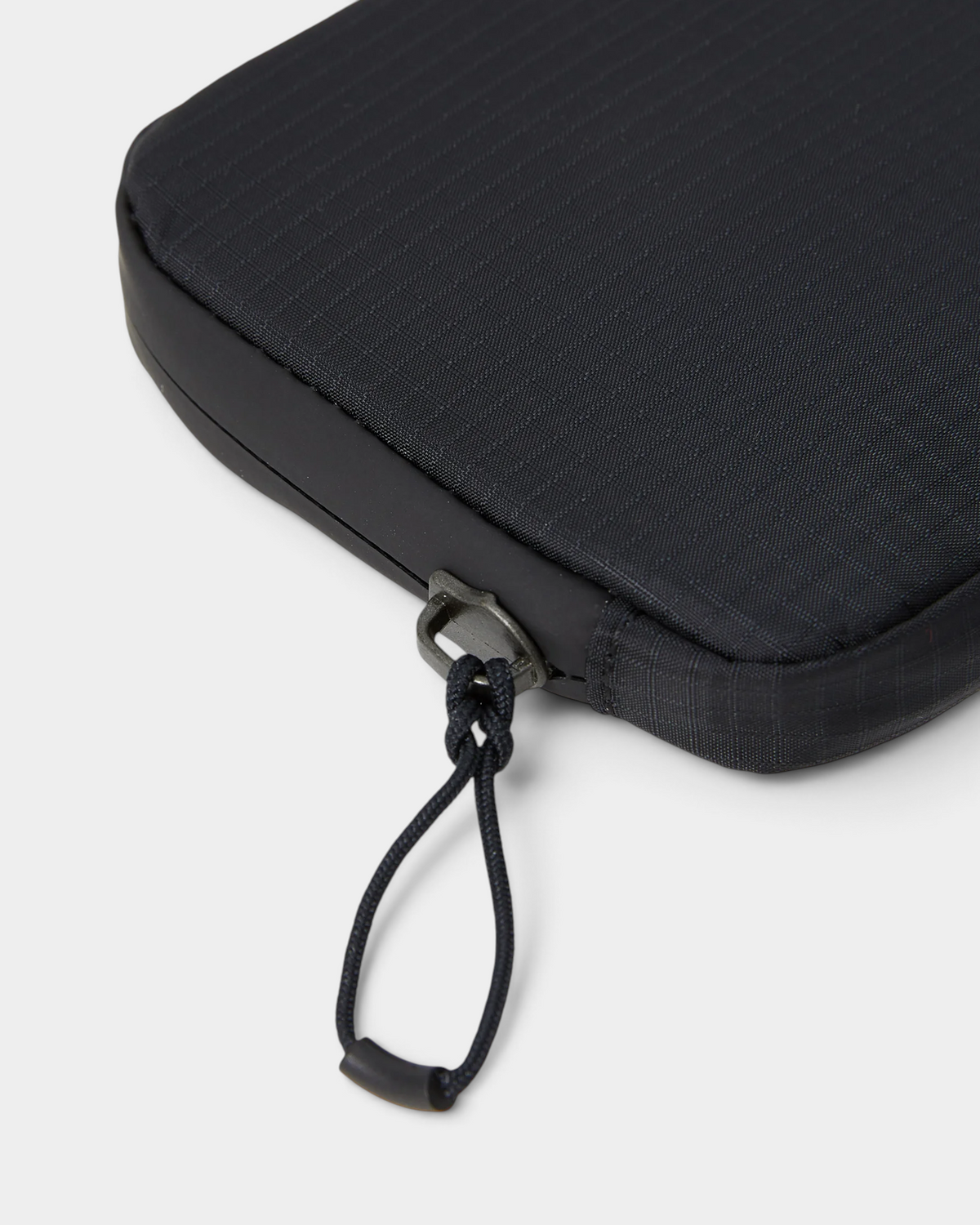Close up of the corner of the Salomon ACS Essentials Case in black, showing the ripstop weave, the bonded edge trim and the zip slider with its knotted cord pull