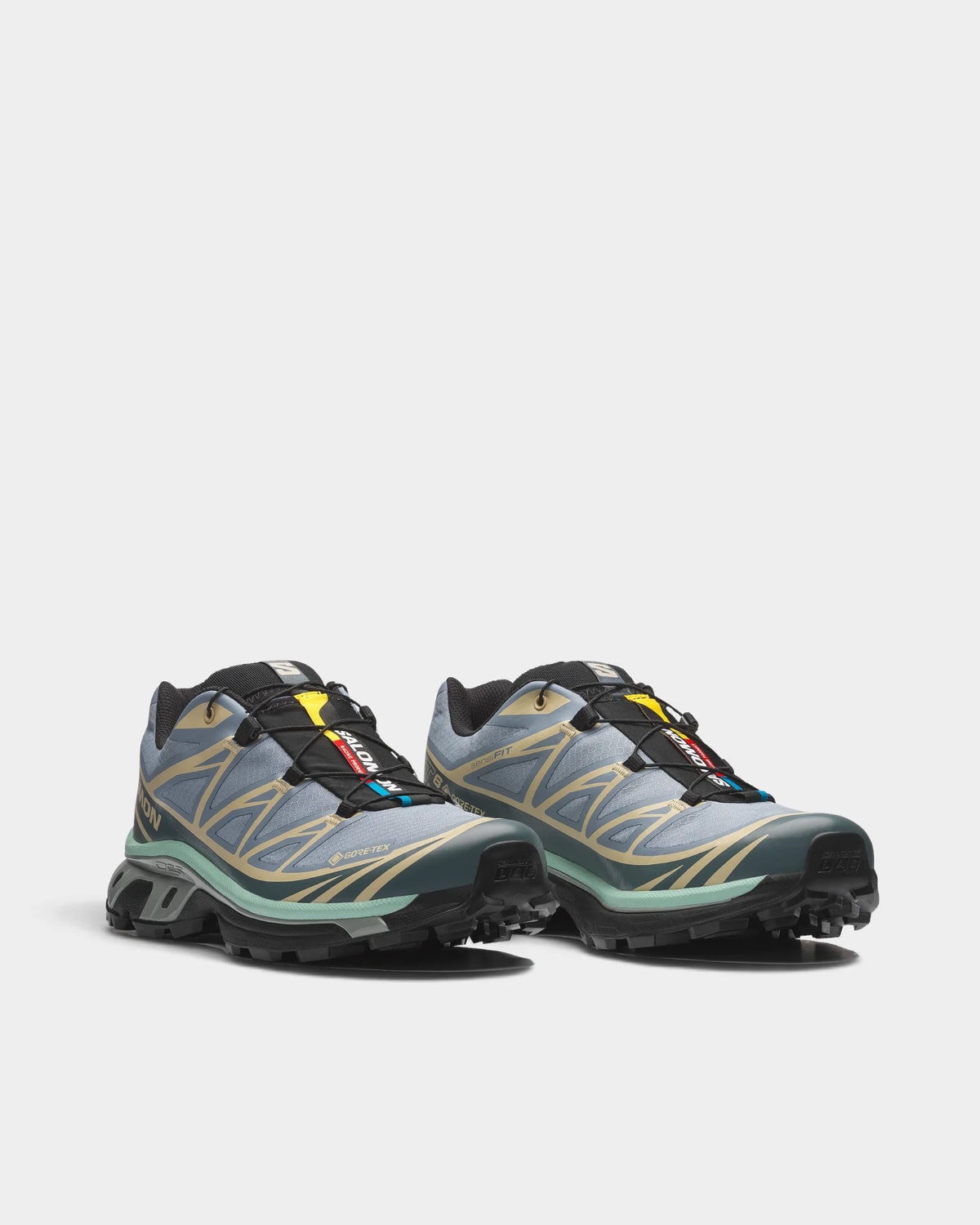 Salomon XT-6 Gore-Tex Shoes in Tradewinds/Stormy Weather/Bog, both shoes from a three-quarter front angle, showing the light blue-grey upper with sand overlays and dark green accents on a black sole