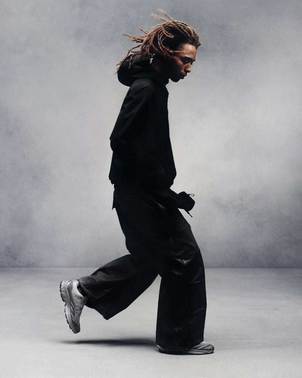 Salomon XT-EVO Shoes in Alloy/Castlerock/Footwear Silver, person mid-stride in profile against a grey studio backdrop, dressed in black, wearing the shoes