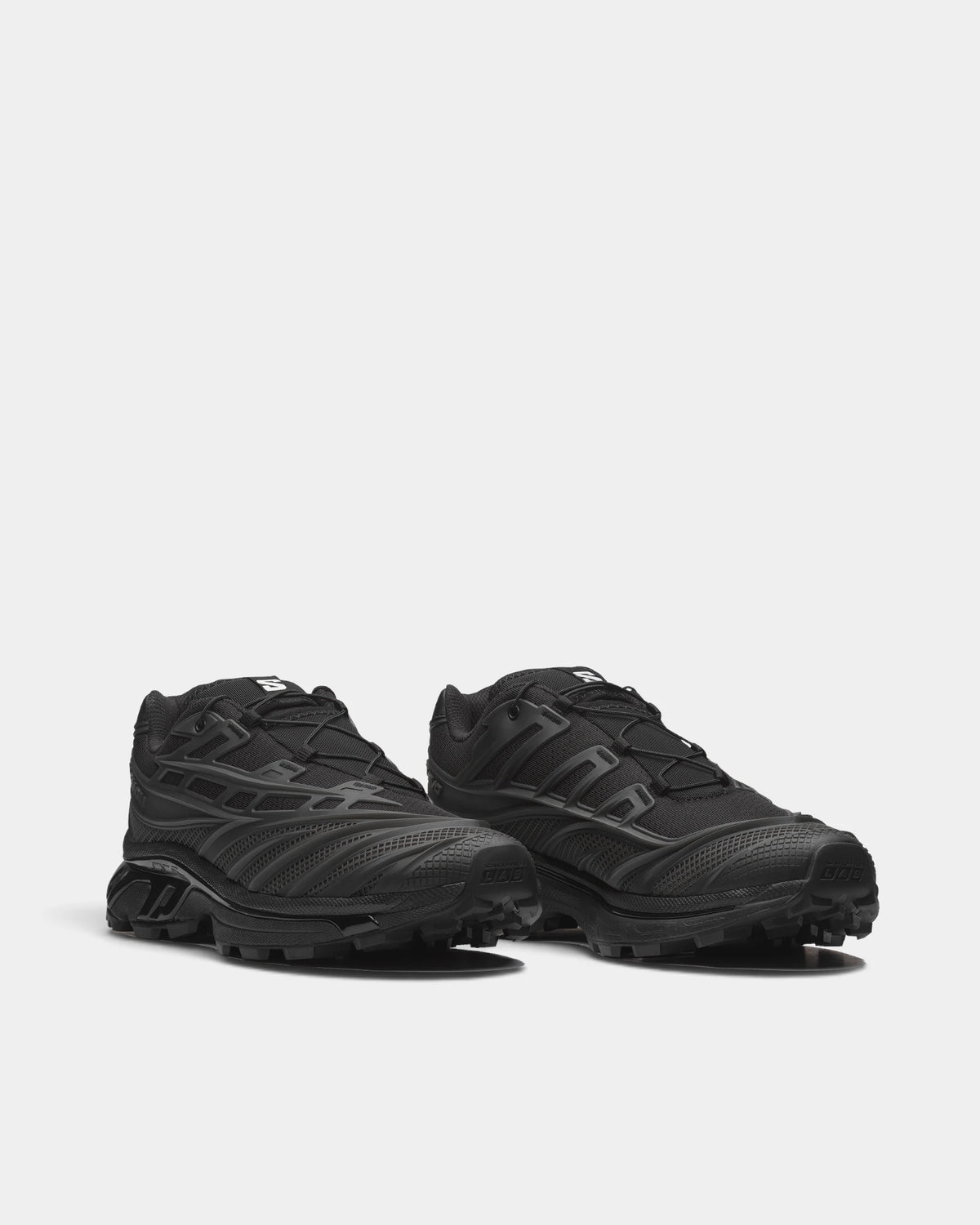 Salomon XT-EVO Shoes in Black/Black/Asphalt, both shoes from a three-quarter front angle, showing the all-black layered upper on a black sculpted sole