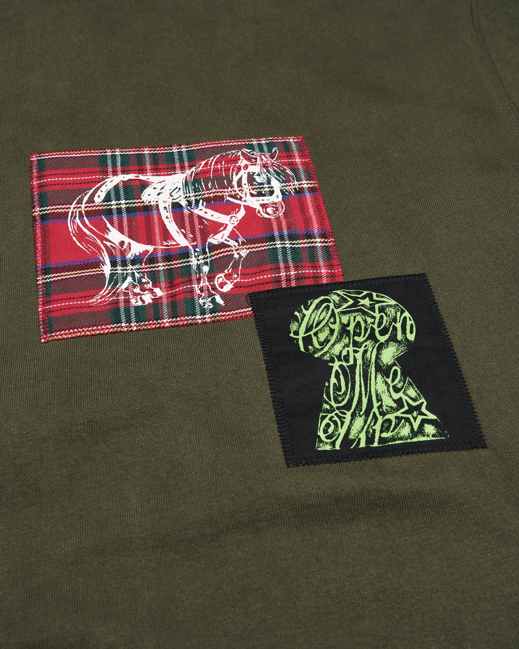Lockwood Avenue Token Carly zip-up hoodie in olive green with printed and sewn patches, close up of a red tartan patch and a black patch