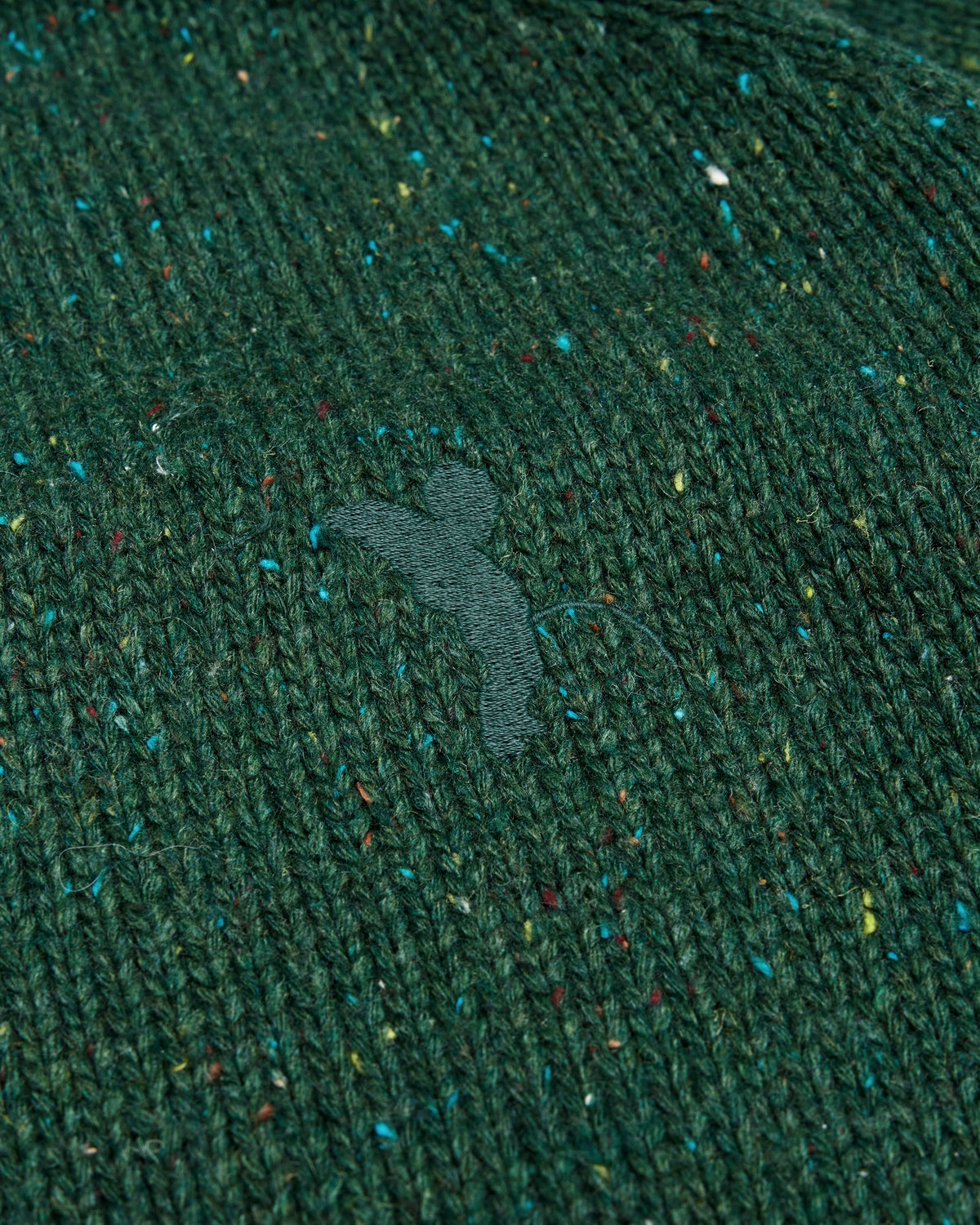 Lockwood Avenue Token Chains sweater, a flecked dark green chunky knit with orange chain jacquard on the sleeves, close up of the knit and the tonal chest embroidery