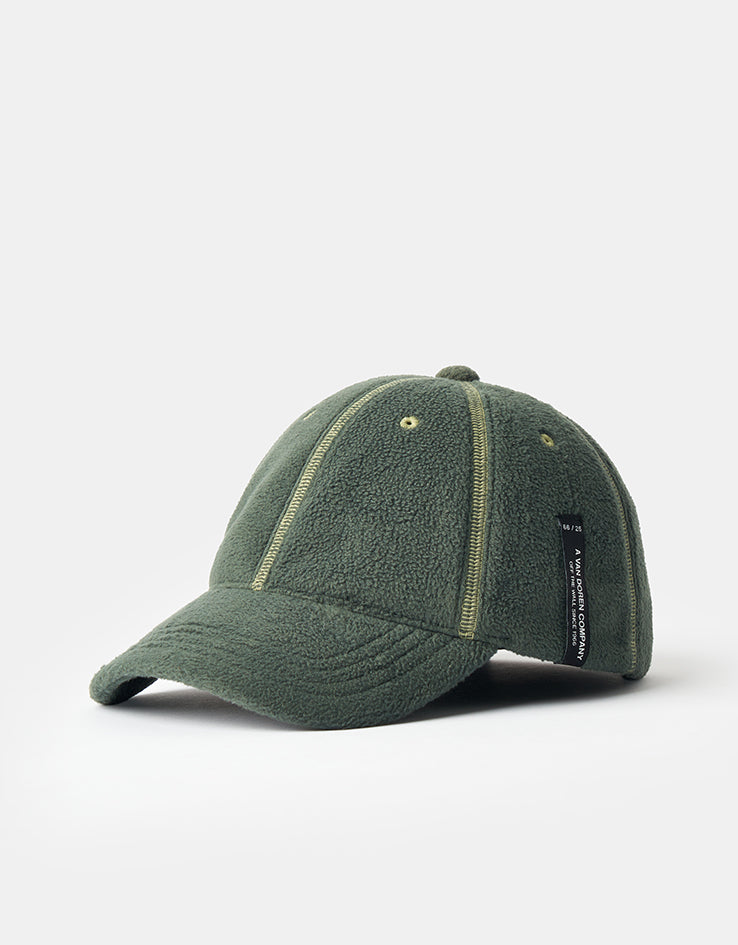 Vans Doren Curved Bill Jockey Cap in Pine Forest green, three-quarter front view of the fleece cap showing the curved bill, pale contrast stitching along the panel seams and the black woven Van Doren label on the side