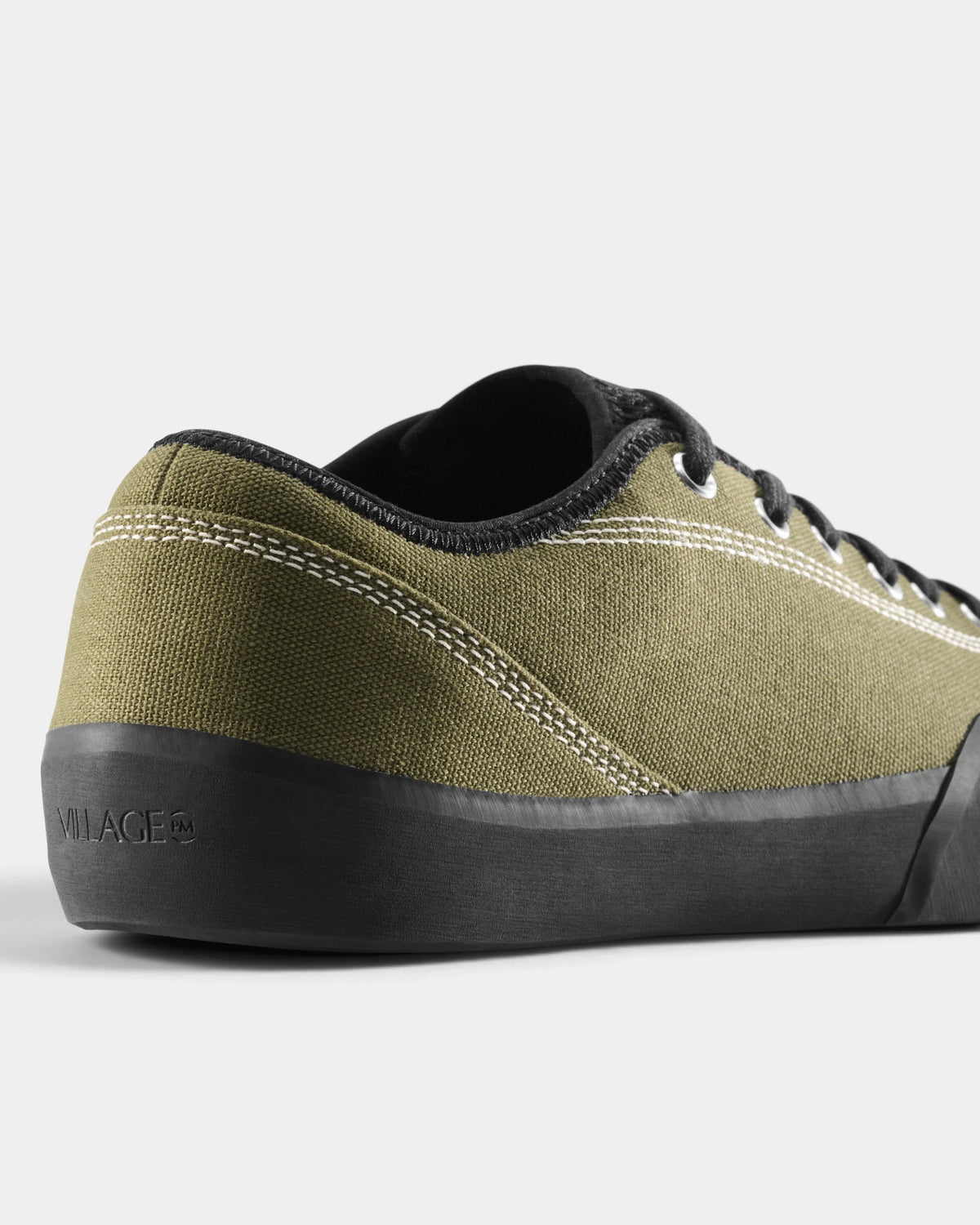 Village PM 1.30PM Canvas Shoes in Olive/Natural Black: a close three-quarter view of the heel and the outer side. A olive canvas low-top skate shoe on a natural black gum outsole.