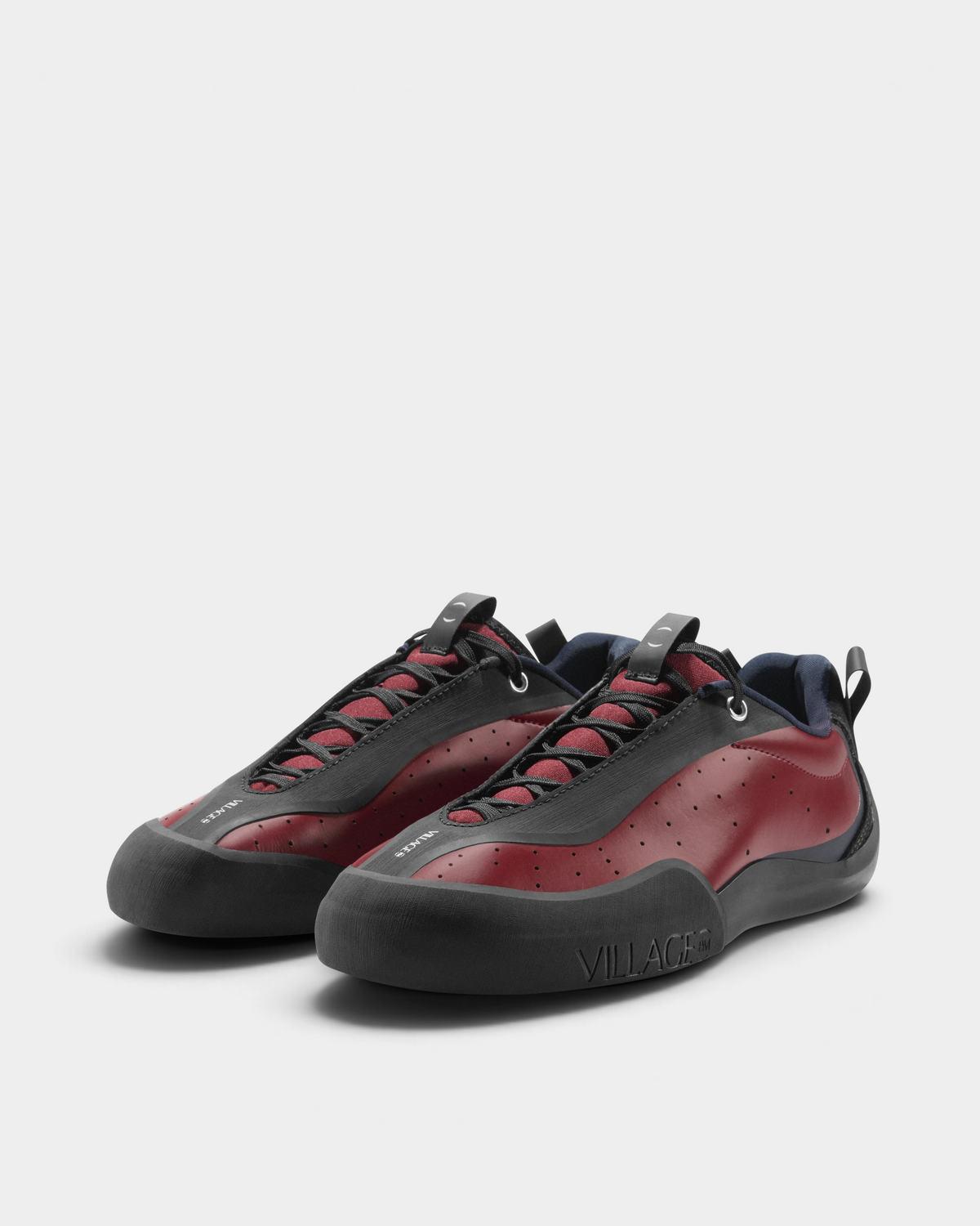 Village PM 2PM Synth Leather Shoes in Red/Natural Black: a red perforated leather low-top skate shoe with black overlays and a black sole, the pair seen at an angle from the front