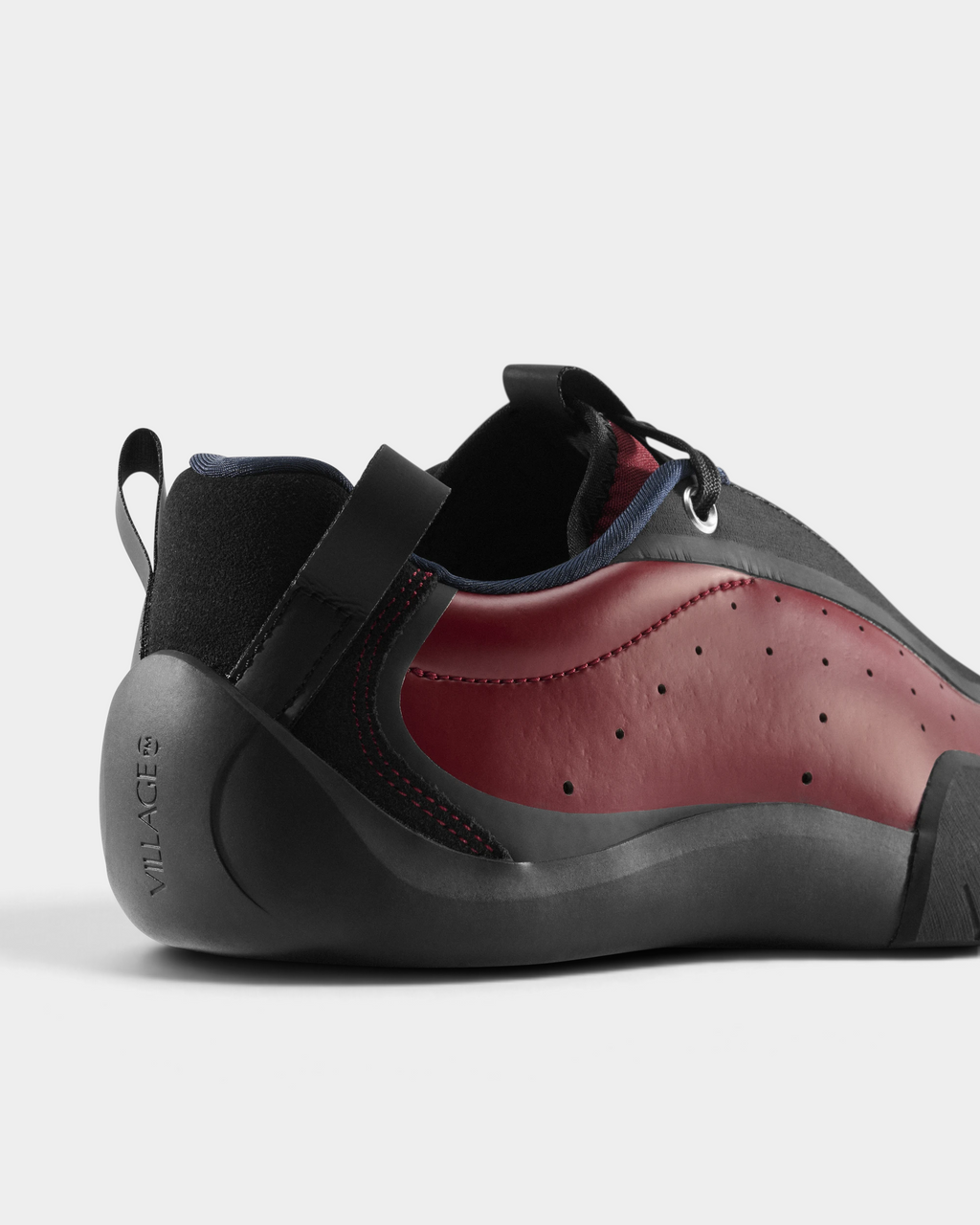 Village PM 2PM Synth Leather Shoes in Red/Natural Black: a red perforated leather low-top skate shoe with black overlays and a black sole, seen from behind at an angle, the heel and the side of the upper