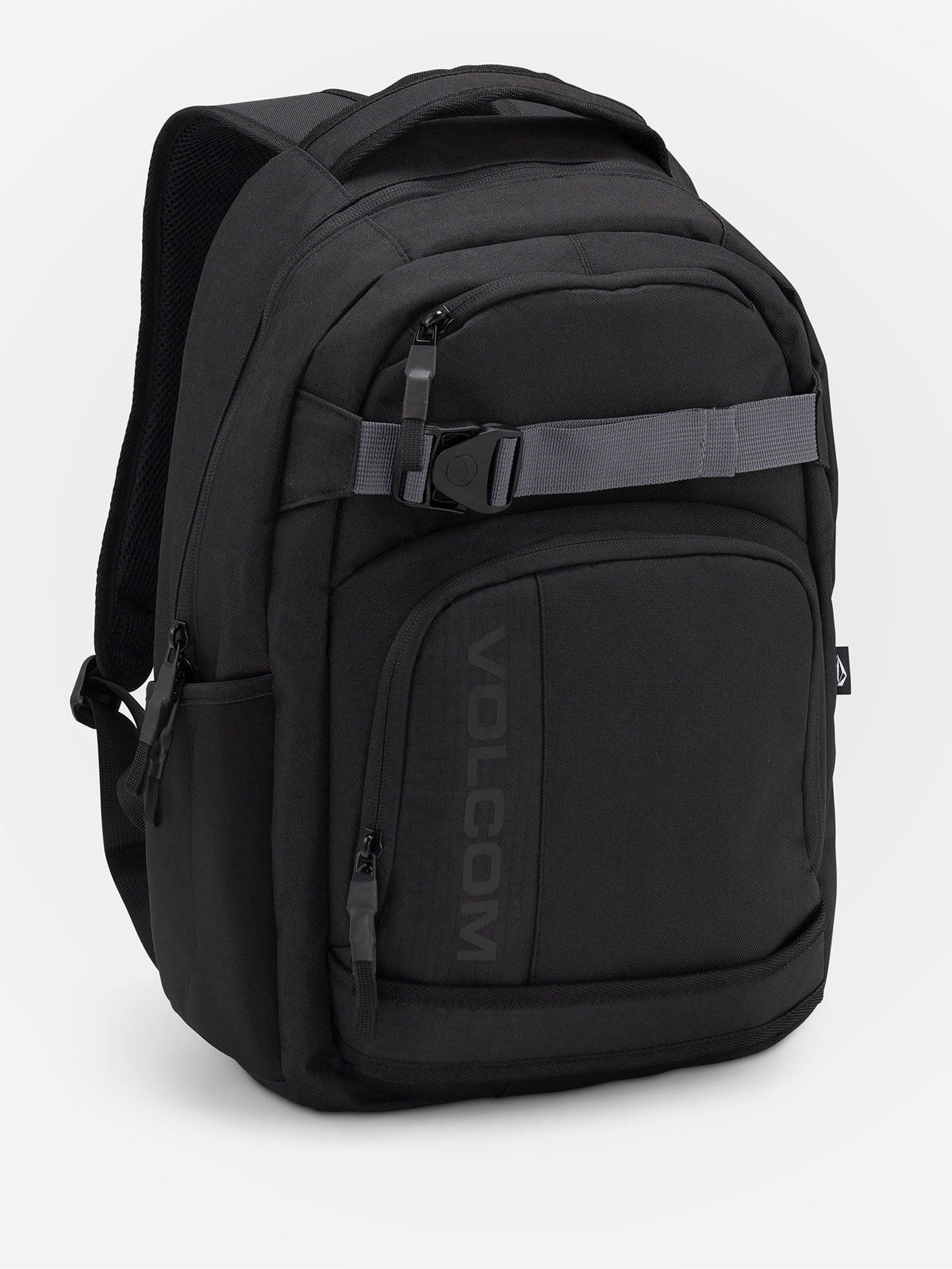 Volcom Everstone Backpack in black, three-quarter front view showing the grey skate strap with branded clip across the front, the embossed VOLCOM wordmark on the lower zip pocket and the side water bottle pocket