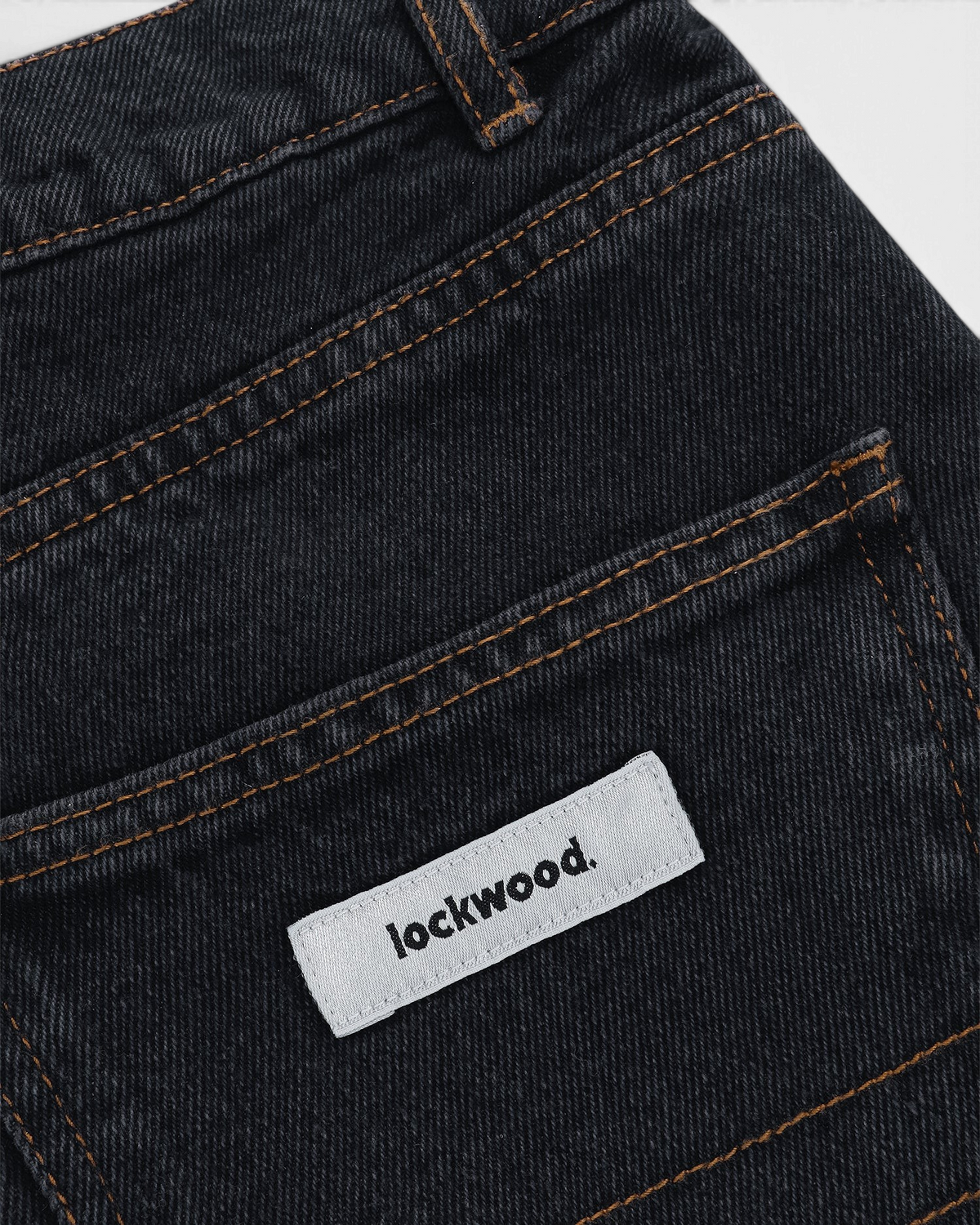 Close-up of the woven lockwood label and brown stitching on the back pocket of the Black Olive Classic Relaxed Jeans